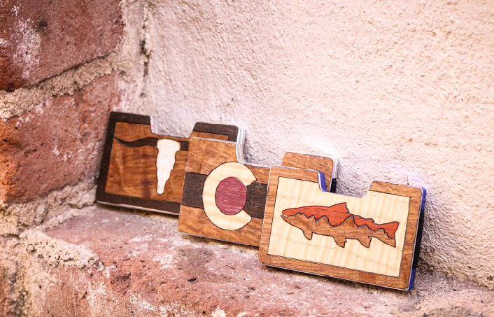 Longhorn, Colorado and trout wallets displayed on a brick ledge