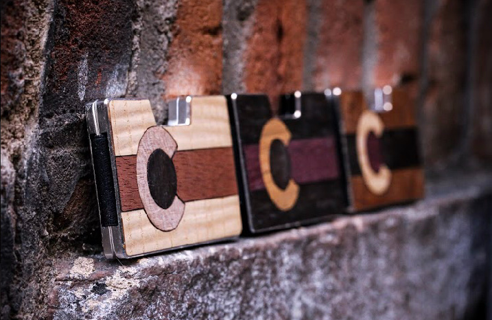 Side view of three Colorado flag wood inlay wallets on brick