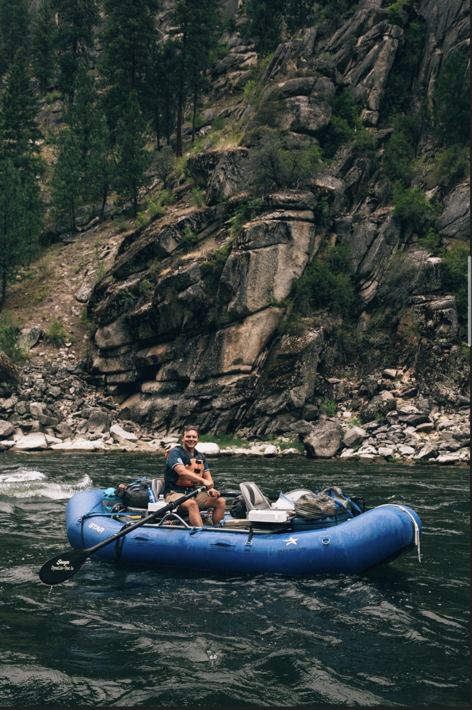 Michael Merritt rowing a raft through a river canyon