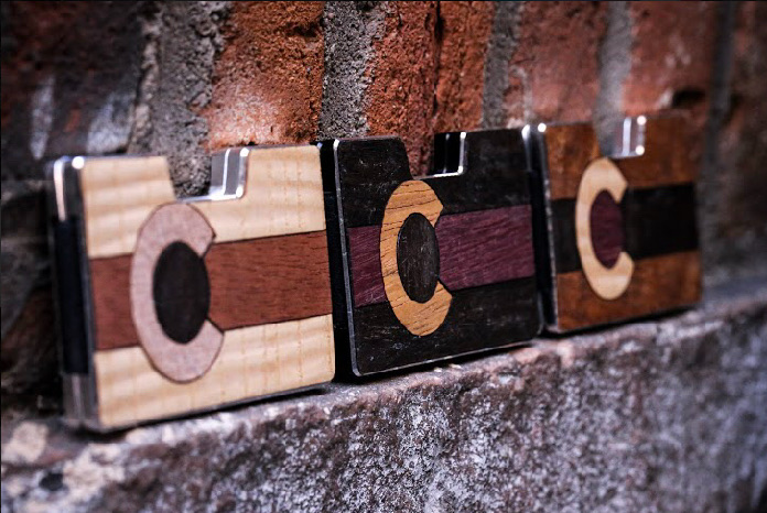 Angled row of three Colorado flag wood inlay wallets on brick