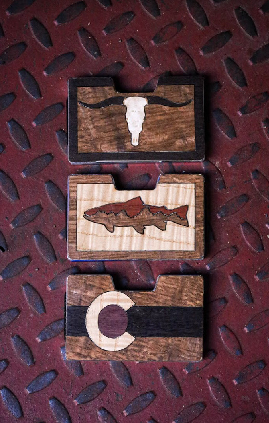 Longhorn, trout and Colorado wallets arranged vertically on metal
