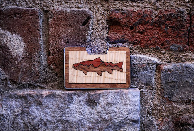 Trout wood inlay wallet displayed against brick